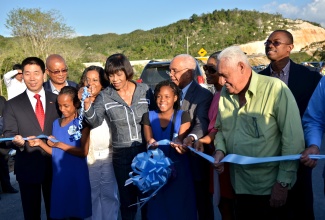 Prime Minister Portia Simpson Miller (6th from right) cuts the ribbon to symbolically open the newly completed section of the North-South Highway from Angels, just outside Spanish Town, to Linstead in St. Catherine. The opening was on Thursday (February 4). Also participating in the opening from left are Ambassador of The People’s Republic of China to Jamaica, His Excellency Niu Qingbao; Mayor of Spanish Town, Councillor Norman Scott; Kelcian Dixon, student of Angels Primary School; Member of Parliament for North Central St. Catherine, Hon Natalie Neita Headley; Angels Primary School student, Janelle Johnson; Minister of Transport, Works and Housing, Dr. Hon. Omar Davies; Minister of Youth and Culture, Hon. Lisa Hanna; Opposition Spokesman on Transport and Works, Mr. Mike Henry ; and Minister of State in the Ministry of Foreign Affairs and Foreign Trade, Hon Arnaldo Brown.