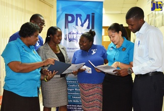 
Members of Staff of the Peace Management Initiative (PMI) Western, in Montego Bay, St. James, discuss programmes  being implemented across western Jamaica. From left are social workers Maxine Matthews and Howard Lewis; Programmes Coordinator, Sheila Pryce Brooks; Violence Interrupter, Brenda-Lee Black Samuels, Violence Interrupter Supervisor, Lavern Johnson and Data Analyst, André Reid. 
