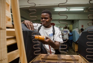 Twenty-two year old Robert Lewis wraps a piece of furniture at Boss Furniture, in Kingston, where he has received permanent employment through a Social and Economic Inclusion of Persons with Disabilities Project done through the Ministry of Labour and Social Security. (FILE)