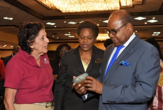 Tourism Minister, Hon. Edmund Bartlett (right), and Permanent Secretary in the Tourism Ministry, Jennifer Griffith (centre), admire a ceramic piece produced by Mustard Seed Ceramics at the ‘Christmas in July’ trade show held at The Pegasus hotel in New Kingston July 27. Looking on is Mustard Seed Ceramics’ Cheryl Mais.