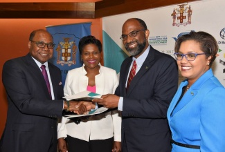 Minister of Tourism, Hon. Edmund Bartlett (left); and Chief Executive Officer, Jamaica National (JN) Group, Earl Jarrett (2nd right), exchange copies of a signed contract, which will see the JN Group providing management and execution services for the United Nations World Tourism Organization (UNWTO) global conference to be held in Jamaica in November. The signing took place at the Jamaica Conference Centre in downtown Kingston on Wednesday (July 26). Also pictured (from 2nd left) are: Permanent Secretary in the Tourism Ministry, Jennifer Griffith; and Managing Director, MCS Group Limited, Onika Miller. MCS Group is a member of the JN Group.