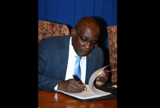 Minister of Education, Youth and Information, Senator the Hon. Ruel Reid, reads over his notes prior to the start of Tuesday’s (March 22) Post-Cabinet press briefing at the Office of Prime Minister in Kingston. 