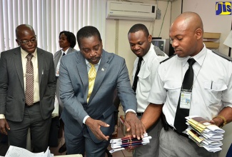 National Security Minister, Hon Robert Montague (second left), is shown newly produced passports by Passport, Immigration and Citizenship Agency (PICA) Immigration Officer,  Christopher Walker (second right), during a tour of the agency’s head office on Constant Spring Road in St. Andrew. Observing (from left) are State Minister, Senator the Hon. Pearnel Charles Jr.; and Immigration Officer, Errol Williams.

