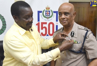 Minister of National Security, Hon. Robert Montague, places a Jamaica Constabulary Force (JCF) 150th anniversary pin on the lapel of Police Commissioner, George Quallo. The Minister handed over 14,000 pins during a ceremony at the Police Commissioner’s offices in St. Andrew on January 11.  

