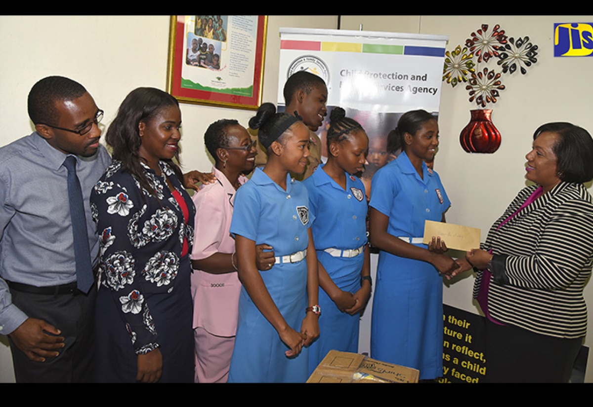 Chief Executive Officer (CEO), Child Protection and Family Services Agency (CPFSA), Rosalee Gage-Grey (right), receives a cheque valued at $100,000 from President of the St. Catherine High School Peer Counsellor Group, Jaunel Johnson (second right), towards the rebuilding of the Walker’s Place of Safety in Kingston.  Sharing the moment (from left) are guidance counsellors Kemar Hayden, Olivette Douglas Halstead, and Rosie McLeggon Hinds; and peer counsellors Breanna Grant, Brianna Powell and Tevonie Pearce. The cheque and 12  boxes comprising clothes, books and toys were donated under the Love Care Project, which was organised by the peer counsellors at the school. The handover took place at the CPFSA’s downtown Kingston offices on Monday (March 19). 