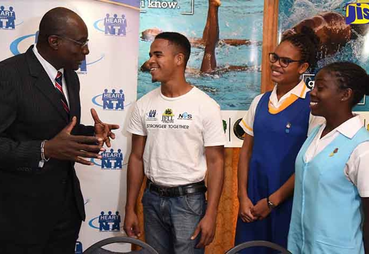 Minister of Education, Youth and Information, Senator the Hon. Ruel Reid (left), converses with three of the 500 youth volunteers for the upcoming CARIFTA Aquatics Championship 2018, in Jamaica. They are (from left) Relando Ulett, Courtnea James and Britney Williams. Occasion was the signing of a memorandum of understanding (MOU) between the HEART Trust/NTA and the Amateur Swimming Association of Jamaica, on January 24,at the University of the West Indies (UWI) Mona Campus in St. Andrew. The agreement will facilitate the engagement of 500 youngsters at the upcoming CARIFTA Aquatics Championship 2018, in Jamaica.