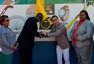 Minister of Education, Senator the Hon. Ruel Reid (second left) and Japanese Ambassador, His Excellency Hiromasa Yamazaki (third left),  clasp hands following the unveiling of a plaque marking the official handover of the recently renovated Warsop Primary and Infant School in Trelawny on Tuesday, February 27.   At left is Member of Parliament for Trelawny Southern, Marisa Dalrymple-Philibert and Principal of the school, Stephanie Codling-Smith.