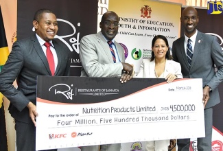 Minister of Education, Youth and Information, Senator the Hon. Ruel Reid (second left), accepts a representational cheque valued at $4.5 million from  Marketing Director, Restaurants of Jamaica (ROJ), Tina Matalon (second right), during a ceremony at the Ministry’s National Heroes Circle offices on Wednesday (March 14). Also pictured (from left) are State Minister in the Education Ministry, Hon. Floyd Green, and Brand Manager, ROJ, Andrei Roper. The funds will provide support to the Government’s national school-feeding programme.