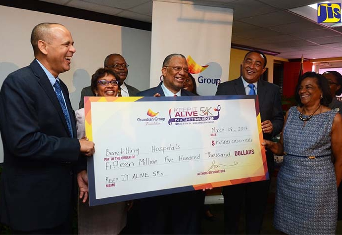 Minister of Health, Dr. the Hon. Christopher Tufton (second right); President, Guardian Life Limited, Eric Hosin (left); President, Guardian General Insurance Jamaica Limited, Karen Bhoorasingh (second left); President of the People’s National Party,  Dr. Peter Phillips (centre) and Senior Lecturer and Head Anaesthetist, Intensive Care, University Hospital of the West Indies, Dr. Hyacinth Harding Goldson hold a symbolic cheque valued $15.5 million that will be used to benefit four hospitals across the island. Occasion was the official launch of the Guardian Group Foundation Keep it Alive 5K runs at the Guardian Life offices at 12 Trafalgar Road in Kingston, today (March 28). Others sharing in the moment (background left) are Chief Executive Officer, St. Ann’s Bay Hospital, Leo Garel; Senior Administrator, Cornwall Regional Hospital, Keriesha Bell Cummings; and Operations Manager at the Mandeville Regional Hospital, Marcia Francis. The race dates for this year are Saturday, May 27 in Kingston and Saturday, June 3 in Montego Bay.