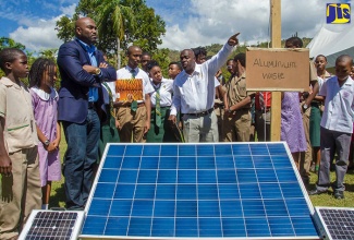 Minister of Science, Energy and Technology, Dr. the Hon. Andrew Wheatley (left), listens as Conrad Brown (right), explains the features of his innovation, at the Science in the Gardens event held at the Hope Botanical Gardens, St. Andrew recently.  Mr. Brown was the winner in the Energy category at the 2016 National Innovation Awards. Also looking on are students from St. Jago High School in St. Catherine as well as students from Saints Peter and Paul Preparatory, St. Andrew.