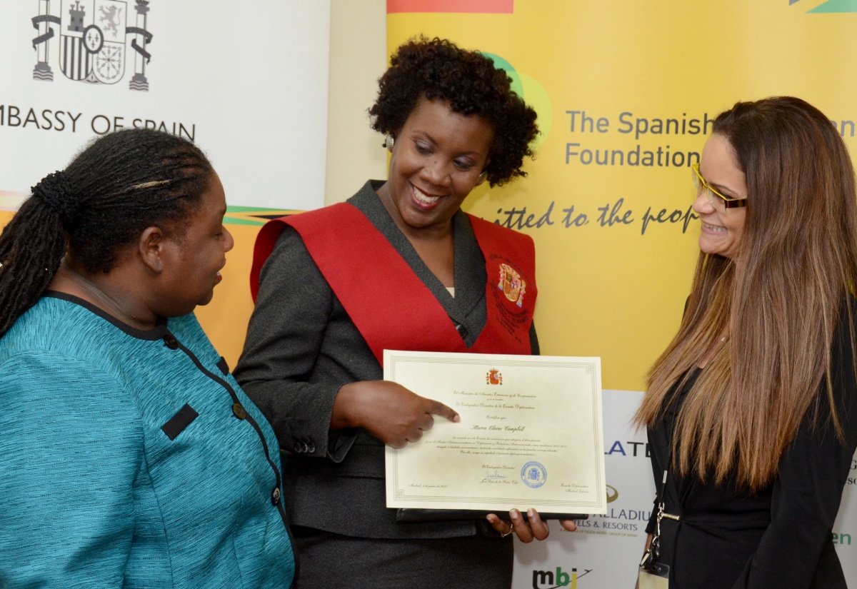 Protocol Officer in the Ministry of Foreign Affairs and Foreign Trade, Marva Campbell (centre), shows her Certificate of Attendance, obtained from the prestigious Diplomatic School in Madrid, Spain, to the Ministry’s Director of Training, Geraldine Myles (left); and Spanish-Jamaican Foundation (SJF) General Manager, Karen Donaldson, during a recent welcome reception held for her at the offices of the Embassy of Spain and SJF, in New Kingston. Mrs. Campbell pursued a Masters Degree in Diplomacy and International Relations at the institution during the 2014/15 academic year, and is currently preparing her thesis for submission to complete the programme, following which she will be conferred with her degree. 
