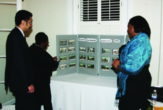 Jamaica’s Ambassador to the United States, His Excellency, Stephen Vasciannie (left), and Deputy Chief of Mission at the Embassy of Jamaica, in Washington, D.C.,  Marsha Core Lobban (right), are given details on the collection of Jamaican postcards on display at an exhibition mounted at the Embassy, by Jamaican Speech Pathologist, Marva Shand McIntosh, following the engagement’s opening ceremony on December 3. The exhibition titled: “Greetings from Jamaica, A Country of History in Postcards”, features over 200 authentic postcards dating back to 1877.