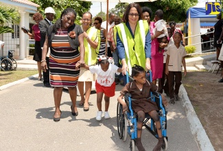 Labour and Social Security Minister, Hon. Shahine Robinson (right), escorts a student of the Stimulation- Plus Early Childhood Development Centre in Rockfort, Kingston, to the site of the facility’s expansion project, for which ground was broken during a ceremony on Tuesday, April 25. Accompanying her are Director of the Early Stimulation Programme, Antonica Gunter Gayle (left); Permanent Secretary in the Ministry, Colette Roberts Risden (2nd left); and Councillor for the Springfield Division in Eastern Kingston, were the Centre is located, Lorraine Dobson (right).  