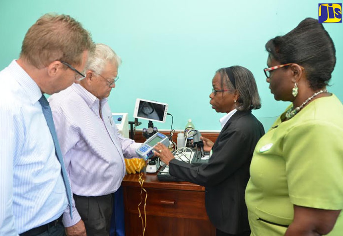 Industry, Commerce, Agriculture and Fisheries Minister, Hon. Karl Samuda (second left), listens to Lab Supervisor, Althea Lawson (second right), as she explains the functions of the equipment donated by the European Union (EU), at the Sugar Industry Authority (SIA) inaugural post-crop seminar, at the Sugar Industry Research Institute (SIRI) in Mandeville, on September 21. Looking on (from left) are Head of Cooperation of the EU, Achim Shaffert, and Acting Director of Research at SIRI, Dr. Maureen Wilson. 