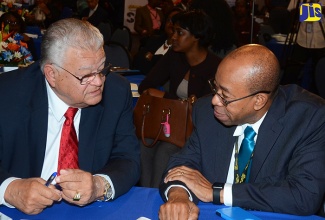 Minister of Industry, Commerce, Agriculture and Fisheries, Hon. Karl Samuda (left), converses with Chief Executive Officer, PetroCaribe  Development Fund, Dr. Wesley Hughes, at the Jamaica Stock Exchange’s (JSE) 12th Regional Investment & Capital Market Conference on Wednesday (January 25), at The Jamaica Pegasus hotel, New Kingston.