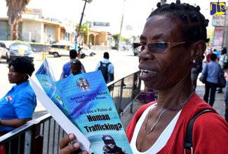 Violet Landell reads one of the brochures on human trafficking handed to her in Half-Way Tree, following the launch of the National Task Force Against Trafficking in Persons tour at the Ministry of Justice in Kingston on March 28. 