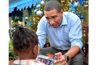 Prime Minister, the Most Hon. Andrew Holness, presents a gift to a child at the annual Christmas treat he hosted along with his wife, the Most Hon. Juliet Holness, at Vale Royal on Thursday (December  8). The youngsters, who are wards of the State, were treated to gifts, rides and a range of fun activities for the day.