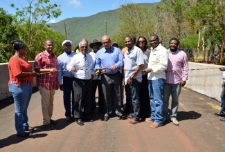 State Minister for Transport, Works and Housing, Hon. Richard Azan (centre),  cuts the ribbon to officially open a bridge in Bigwoods, South West St. Elizabeth on April 16, which was constructed at a  cost of  $10.1 million. Joining Mr. Azan for the occasion are: Black River’s Mayor, Councillor Everton Fisher (3rd left); Councilllor for the Pedro Plains Division, Jeremy Palmer (4th left); Member of Parliament for South West St. Elizabeth, Hugh Buchanan (4th right); Project Manager at the Jamaica Emergency Employment Programme (JEEP), Carolyn Gardener (3rd right);  Member of Parliament for South East St. Elizabeth, Richard Parchment (2nd right); as well as representatives of the National Works Agency (NWA) and  community members. 