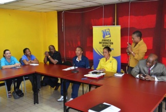 Director of Production at the Jamaica Information Service (JIS), Miss Enthrose Campbell  (standing),  speaking  at a debriefing session with members of a delegation from Botswana, who were in the island on a communication benchmarking  mission with the JIS, at the agency's headquarters on September 23. The delegation, which arrived in the island on September 17, left the island on September 23. Listening keenly (from
right) are:  Honorary Consul of Botswana in Jamaica, Dr. Henley Morgan; Chief Executive Officer of the JIS, Mrs. Donna-Marie Rowe;  Deputy Permanent Secretary, Ministry of State President (Botswana), Mr. Mogomotsi Kaboeamodimo, who headed the delegation;  Director, Information Services Department, Mr. Russ Molosiwa; Manager,  Radio, Ms. Keitirile Mathapi; and Managing Editor, Botswana Daily News, Ms. Charmaine Revaka.
