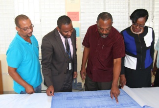 Minister of State in the Office of the Prime Minister and Member of Parliament for Eastern Westmoreland, Hon. Luther Buchanan (2nd right), reviews aspects of the blueprint for the construction of five new classrooms at the Belmont Academy in the parish with Project manager, Tropical Metal Products Ltd., Patrick McKenzie (left); Principal of the school, Rayon Simpson (2nd left); and Regional Director in the Ministry of Education region 4, Hillary Foster. The signing ceremony was held on Thursday, February 6, on the school compound.