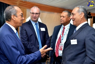 Minister without Portfolio in the Ministry of Economic Growth and Job Creation, Hon. Dr. Horace Chang (left), in dialogue with (from second left), Chairman, Norman Manley International Airport (NMIA), Paul B. Scott; President, Airports Authority of Jamaica, Audley Deidrick; and Custos of Clarendon, William Shagoury. Occasion was a Bidders Conference for the divestment of the NMIA on the grounds of the facility in Kingston on September 26.