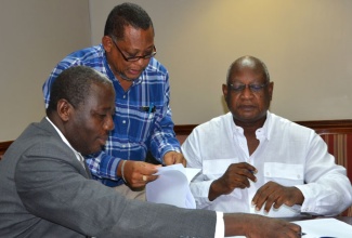 Permanent Secretary in the Ministry of Water, Land, Environment and Climate Change, Dr. Alwin Hales (left), is about to affix his signature to copies of contracts which will see four local experts conducting an assessment exercise on the country’s vulnerability and adaptation to climate change. Overseeing the process (at second left) is  Project Administrator, Third National Communication, Clifford Mahlung. The consultants, who will be carrying out a total of 15 case studies, are (from third left): Physicist and Climatologist, Professor Anthony Chen; Executive Chairman and Principal Consultant, Conrad Douglas and Associates Limited, Dr. Conrad Douglas; and Director, Climate Studies Group, University of the West Indies, Mona, Professor Michael Taylor. Lead Consultant, Third National Communication, Dr. Donovan Campbell, is the other consultant. The contracts were signed during a ceremony at the New Kingston offices of the Ministry on July 16. The studies are to be carried out as part of the Government’s ongoing work in preparing Jamaica’s Third National Communication and First Biennial Update Report to the United Nations Framework Convention on Climate Change (UNFCC), to which the country is party. 