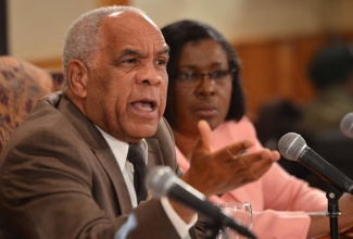 Minister of Transport, Works and Housing, Dr. the Hon. Omar Davies, fields questions from journalists during a Jamaica House press briefing at the Office of the Prime Minister on September 11. Looking on in the background is Permanent Secretary in the Ministry, Audrey Sewell.