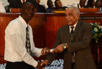 Minister of Transport, Works and Housing, Hon. Dr. Omar Davies (right) presents Phillip Brown of the Western Transport Region with his certificate for successfully completing the Transport Authority’s Public Passenger Vehicle Driver and Conductor Training Programme. Occasion was a certification ceremony for the 541 participants held on Wednesday, August 28, at the Jamaica Conference Centre, downtown Kingston.