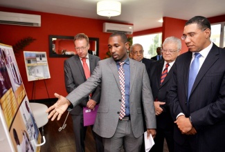 Prime Minister, the Most Hon. Andrew Holness (right), listens as Team Leader, Chemistry Department, Bureau of Standards Jamaica (BSJ), Dwyte Bremmer (second right), highlights some of the capacity building interventions that have been undertaken in food testing laboratories under the Economic Partnership Agreement (EPA) Capacity Building projects with the European Union (EU). The Prime Minister was viewing a display which was mounted at an export forum at the Spanish Court Hotel in New Kingston on June 2. In the background (from left) are: Head of Operations for the Delegation of the EU to Jamaica, Achim Schaffert; Director General of the Planning Institute of Jamaica (PIOJ), Colin Bullock; and Minister of Industry, Commerce, Agriculture and Fisheries, Hon. Karl Samuda. The forum, hosted by the PIOJ, aimed to  highlight the work carried out over the years under the EPA Capacity Building projects with the EU to strengthen Jamaica’s quality infrastructure and food safety systems.