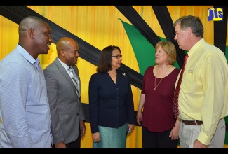 Minister of Labour and Social Security,  Hon. Shahine Robinson (centre), in discussion with Managers at Gebbers Farms in Washington, United States, Catherine Grandy (second right) and Bob Grandy (right), after the Gebbers Farms management and workers academic grants presentation ceremony  on May 5 at the Ministry’s North Street office. Listening are Supervisor at Gebbers Farms, Eyon Gayle (left) and Liaison Officer, Sheldon Brown.