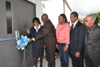 Prime Minister, the Most Hon. Portia Simpson Miller (left), is assisted by Minister of Health, Hon. Dr. Fenton Ferguson (2nd left), in cutting the ribbon, symbolising the official opening of the Oak Glade Health Centre in Kingston, during a special ceremony on Friday, November 15. Also sharing in the moment are (from left): Councillor, Payne Land Division, Audrey Smith-Facey; Board Chairman, South East Regional Health Authority (SERHA), Lyttleton Shirley; and Board Chairman, National Health Fund, Sterling Soares.