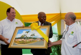 Minister with responsibility  for Housing in the Ministry of Transport, Works and Housing, Hon. Dr. Morais Guy (centre), is presented with a painting of the new Caymanas Country Club Estate housing development in St. Catherine by Chairman and Chief Executive Officer of the developer, New Era Homes 2000 Limited, Leo Taddeo (left), and President, Benedetto Persichilli, during the official opening ceremony on October 23. Dr. Guy was the keynote speaker. Phase one of the development, comprising 264 one and two bedroom units, has been completed, while the second, currently under construction, will provide an additional 420 units.