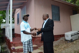 Minister without Portfolio with responsibility for Housing in the Ministry of Transport, Works and Housing, Hon. Dr. Morais Guy (right), presents Resident of Cheswick, St. Thomas, Carl Chambers, with keys to his new two-bedroom home, during a special handing-over ceremony in the parish last year.   