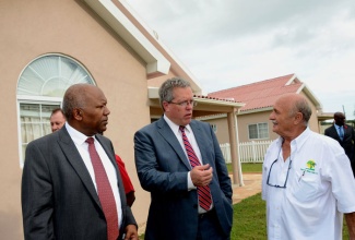 Minister with responsibility  for Housing in the  Ministry of Transport, Works and Housing, Hon. Dr. Morais Guy (left); and New Era Homes 2000 Limited President, Benedetto Persichilli (right), listen to a point being emphasized by Canada’s High Commissioner to Jamaica, His Excellency Robert Ready,  following Wednesday’s (October 23) official opening of the Caymanas Country Club Estate housing development in St. Catherine. Dr. Guy was the main speaker. Phase one of the development, being undertaken by New Era Homes, comprises 264 one and two bedroom units, which have been completed, while the second phase, currently under construction, will provide an additional 420 units.