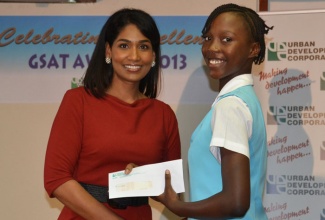 Minister of Youth and Culture, Hon. Lisa Hanna (left), presents a gift voucher to a recipient of the Urban Development Corporation’s (UDC) 2013 Grade Six Achievement Test (GSAT) scholarship award, Shavelle Shaw, during a luncheon at the Jamaica Conference Centre in Kingston, recently. Twenty-nine students, whose parents are employed to the UDC were presented with gift vouchers of $10,000 each.