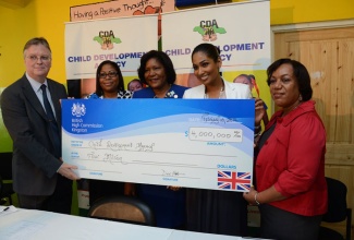 Minister of Youth and Culture, Hon. Lisa Hanna (4th left), seems delighted as  British High Commissioner to Jamaica, His Excellency David Fitton (left), hands over cheque for $4 million to Acting Chief Executive Officer of the Child Development Agency (CDA), Rosalee Gage-Grey (right), to assist girls at the Homestead Place of Safety, in Stony Hill, St. Andrew,  on February 10. Others (from second left) are: Manager at the facility, Sophia Walters, and President of the Rotary Club of St. Andrew, Marie Powell. 