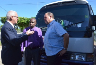 Education Minister, Hon. Rev. Ronald Thwaites (left), converses with Holmwood Technical High School Principal, Paul Bailey (centre), and North East Manchester Member of Parliament, Audley Shaw, during a visit to the institution’s campus in Manchester on  Thursday (Sept. 26). Behind them is one of the two buses currently contracted by the school to provide transportation services for students.

