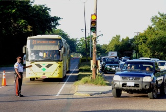 A police officer stops a JUTC bus in the contra-flow bus lane to allow right turning traffic from Nelson Mandela Highway onto Municipal Boulevard to proceed. This took place during the dry run of the designated bus lane trial period on Thursday October 24. 