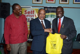 Minister of Agriculture, Labour and Social Security, Hon. Derrick Kellier (centre), receives a bag of local produce from President of the Jamaica Agricultural Society (JAS), Senator Norman Grant (right). Occasion was the launch of ‘Eat Jamaican’ Month on November 5, at the JAS’ downtown Kingston offices. Sharing the moment is State Minister in the Ministry, Hon. Luther Buchanan.