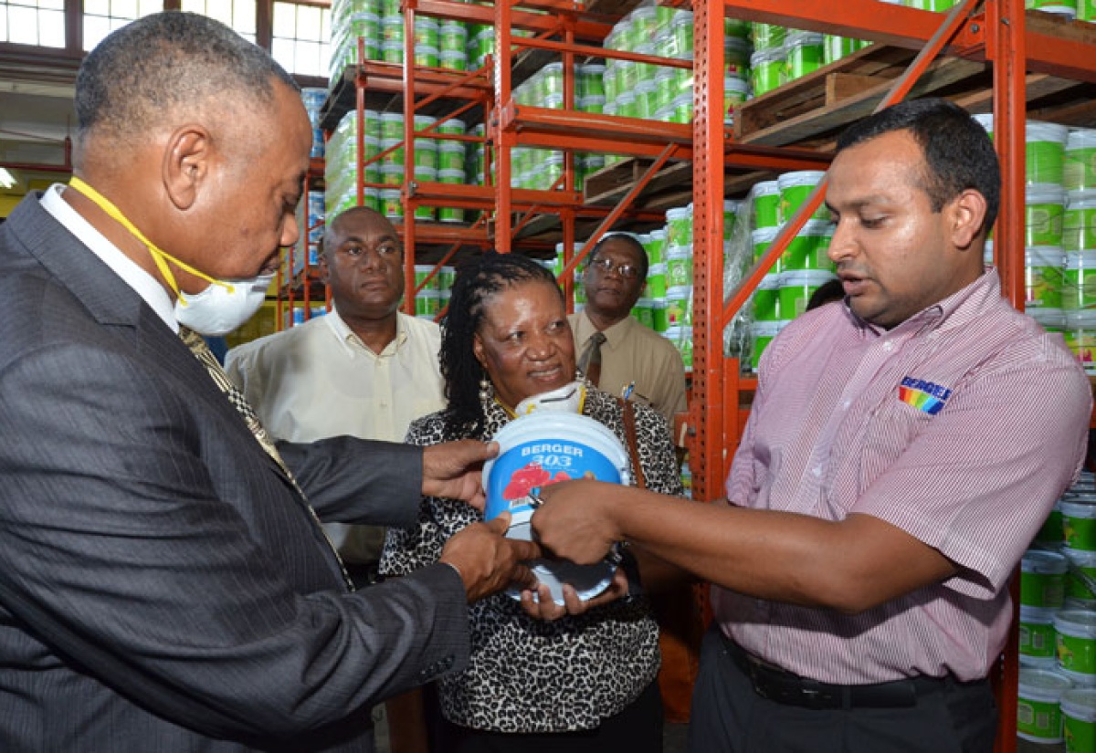 Minister of Labour and Social Security, Hon. Derrick Kellier (left), inspects a bucket of paint being shown to him by Managing Director, Berger Paints, Mustafa Turra (right), during a tour of  the plant on Spanish Town Road, in Kingston, on April 24. Looking on are: Advisor to the Minister, Phyllis Mitchell (centre); Raw Material and Depo Coordinator, Berger Paints, Ronald Fuller (background left) and Chief Technical Director in the Ministry, Errol Miller. 