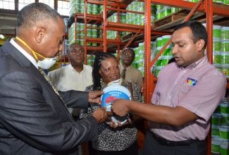 Minister of Labour and Social Security, Hon. Derrick Kellier (left), inspects a bucket of paint being shown to him by Managing Director, Berger Paints, Mustafa Turra (right), during a tour of  the plant on Spanish Town Road, in Kingston, on April 24. Looking on are: Advisor to the Minister, Phyllis Mitchell (centre); Raw Material and Depo Coordinator, Berger Paints, Ronald Fuller (background left) and Chief Technical Director in the Ministry, Errol Miller. 