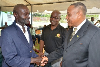 Minister of Labour and Social Security, Hon. Derrick Kellier (right), greets resident of the Golden Age Home, Tanny Johnson (left), while attending a Christmas fair,  held on Wednesday, December 11, at the facility located in Vineyard Town, Kingston. Looking on is Chairman of the home, Fabian Brown.