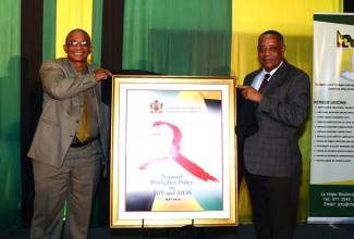 Labour and Social Security Minister, Hon. Derrick Kellier (right), and Director, Occupational Safety and Health Department, Ministry of Labour and Social Security, Robert Chung, unveil the Ministry’s National Workplace Policy on HIV and AIDS,  at the Jamaica Pegasus Hotel, New Kingston, on December 16. Jamaica’s Occupational Safety and Health Profile was also launched by Mr. Kellier.