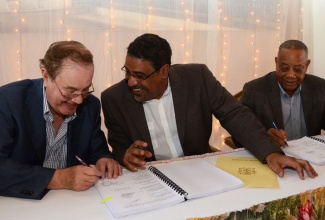 Tourism and Entertainment Minister, Hon. Dr. Wykeham McNeill (centre), having a light  conversation with Chairman of Europe’s third largest hotel chain, Melia Hotels International (MHI), Gabriel Escarrer Julia (left), during the signing of an agreement between MHI and the National Insurance Fund (NIF) for the provision of 400 jobs at the Braco Hotel in Trelawny, which MHI will operate over the next 15 years. Arrangement for the jobs were finalized following discussions involving Dr. McNeill; Labour and Social Security Minister, Hon. Derrick Kellier (right), under whose portfolio the NIF falls.