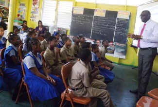 President of the Kiwanis Club of Montego Bay, Floyd Lewis (right), addressing students at the Catherine Hall Primary School in St. James on the Bring Up Grades (BUG) programme, which was launched at the school on October 21. The initiative, which is being spearheaded by Kiwanis International, is aimed at getting students to improve their performance in school.