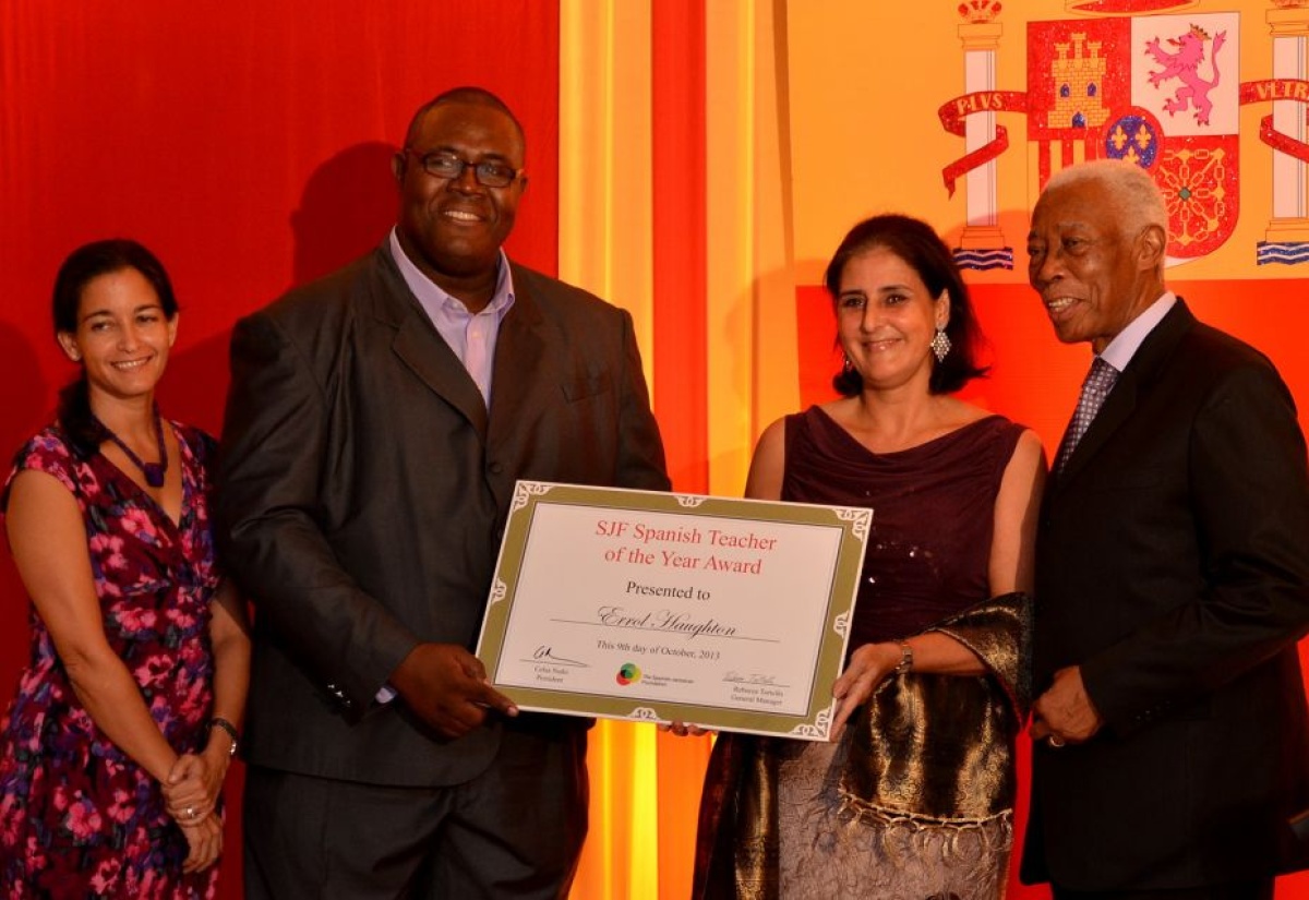 Spanish Ambassador to Jamaica, and President of the Spanish Jamaican Foundation (SJF), Celsa Nuño (second right), presents award to Spanish teacher at the Meadowbrook High School, Mr. Errol Haughton, who was on October 9 announced as the inaugural winner of the Spanish Jamaican Foundation’s Spanish Teacher of the Year Award on October 9. Minister of Foreign Affairs and Foreign Trade, Senator the Hon. A.J. Nicholson, is at right and   General Manager, SJF, Dr. Rebecca Tortello, is at left. Occasion was a reception celebrating Spain’s National Day at the Mona Visitor’s Lodge.