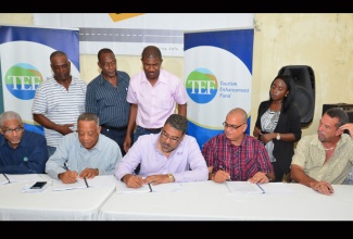 Minister of Tourism and Entertainment,  Hon. Dr. Wykeham McNeill (centre); State Minister for Transport, Works and Housing, Hon. Richard Azan  (3rd right) as well as Member of Parliament for South St. James,  Hon. Derrick Kellier (2nd  left) affix their signatures to the contract for the rehabilitation of the Mocho to Arcadia main road in St. James. The signing took place at the Mocho Community Centre on Friday, September 4. The contract was  witnessed by the Executive Director of the Tourism Enhancement Fund (TEF), Mr. Clyde Harrison (left); Director of the contracting firm, S and G Road Surfacing Materials Limited, Robert Smith (right) and Montego Bay Mayor, Councillor Glendon Harris (standing, second left).