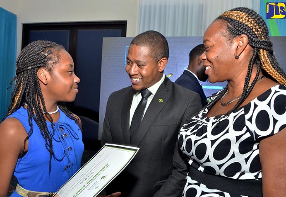 State Minister in the Education, Youth and Information Ministry, Hon. Floyd Green (centre), listens to scholarship awardee, Dexia Dixon (left), at the third staging of the Sagicor Foundation Scholarship Awards ceremony, at The Jamaica Pegasus hotel in New Kingston, on August 24. At right is Dexia’s mother, Sceanie Clayton. 