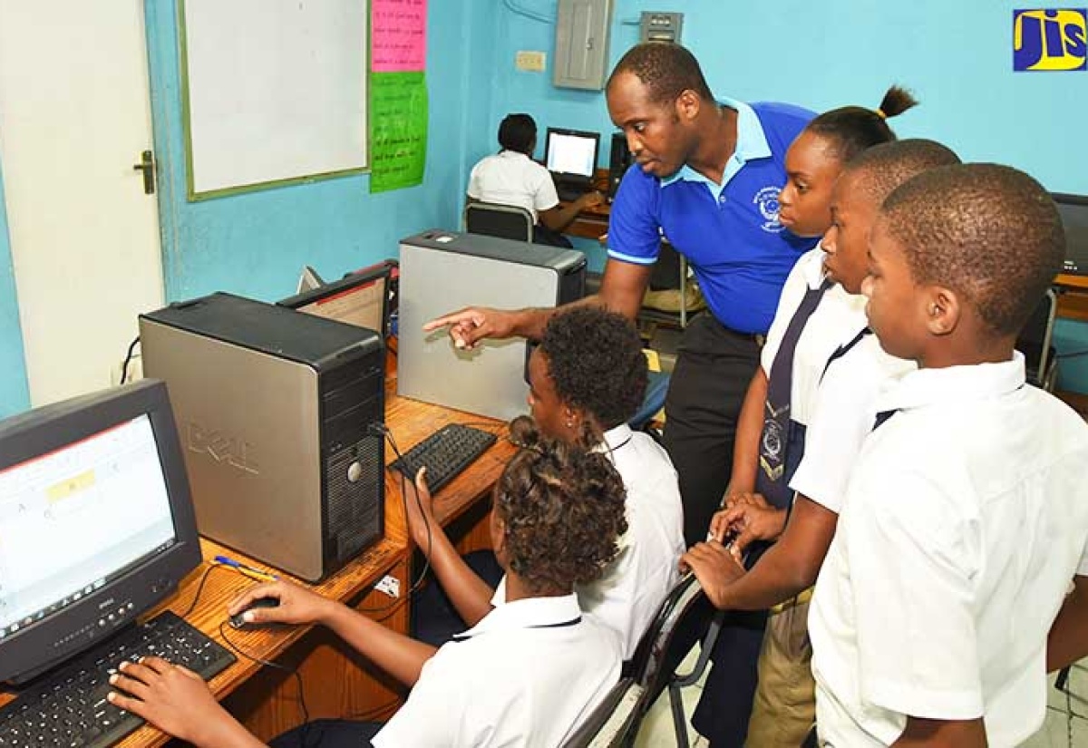 Information Technology teacher at Mico Practising Primary & Junior High School, Dwayne Earle (centre), giving instructions to grade-nine students who will be registered by the institution for the 2018 sitting of Electronic Document Preparation Management in the Caribbean Secondary Education Certificate (CSEC) examinations.