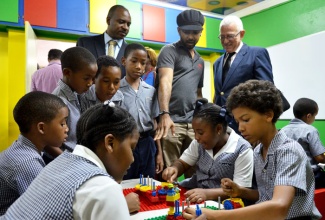 Minister of Education, Hon. Rev. Ronald Thwaites (standing right), observes as students use Legos to build structures, during the official opening of the Mona Preparatory School’s engineering laboratory on September 25, at the school’s premises on Old Hope Road, St. Andrew. Others looking on are Founder of Halls of Learning, Marvin Hall (2nd right); and Board Chairman, Mona Preparatory School, Stefan Wright (left).
